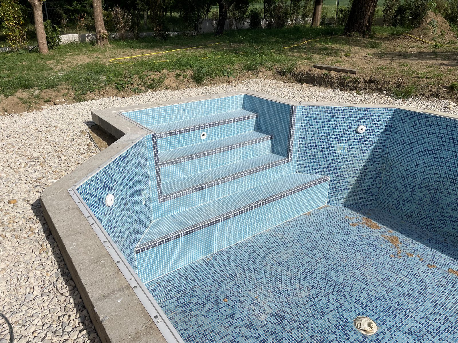 Bassin en cours de finition, escalier d'angle entièrement revêtu de mosaïque bleue